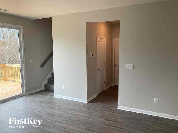 A room with a wooden floor and a staircase leading to the upper floor.