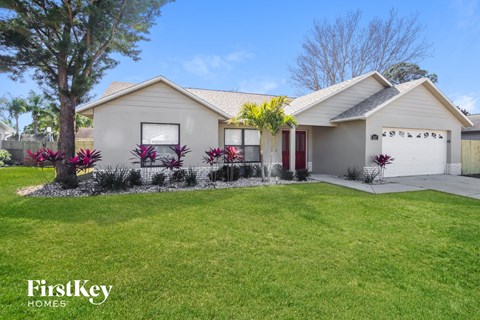 A house with a lawn and a tree in front of it.