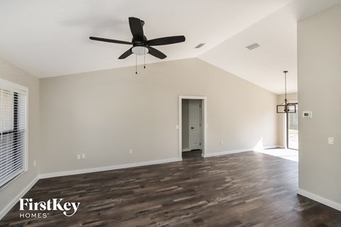 A spacious room with a ceiling fan and wooden flooring.