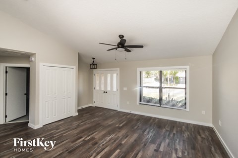 A spacious room with wooden floors and a ceiling fan.