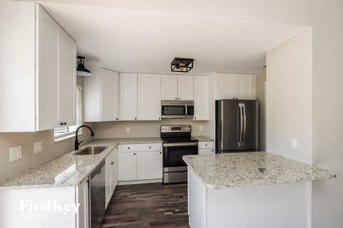 A kitchen with white cabinets and granite countertops.