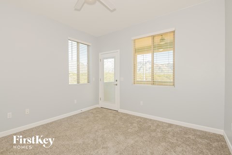 a bedroom with white walls and carpet and a white door and window