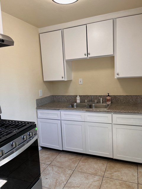 a kitchen with white cabinets and a sink and a stove