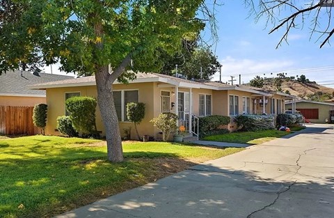 a yellow house with a tree and a sidewalk