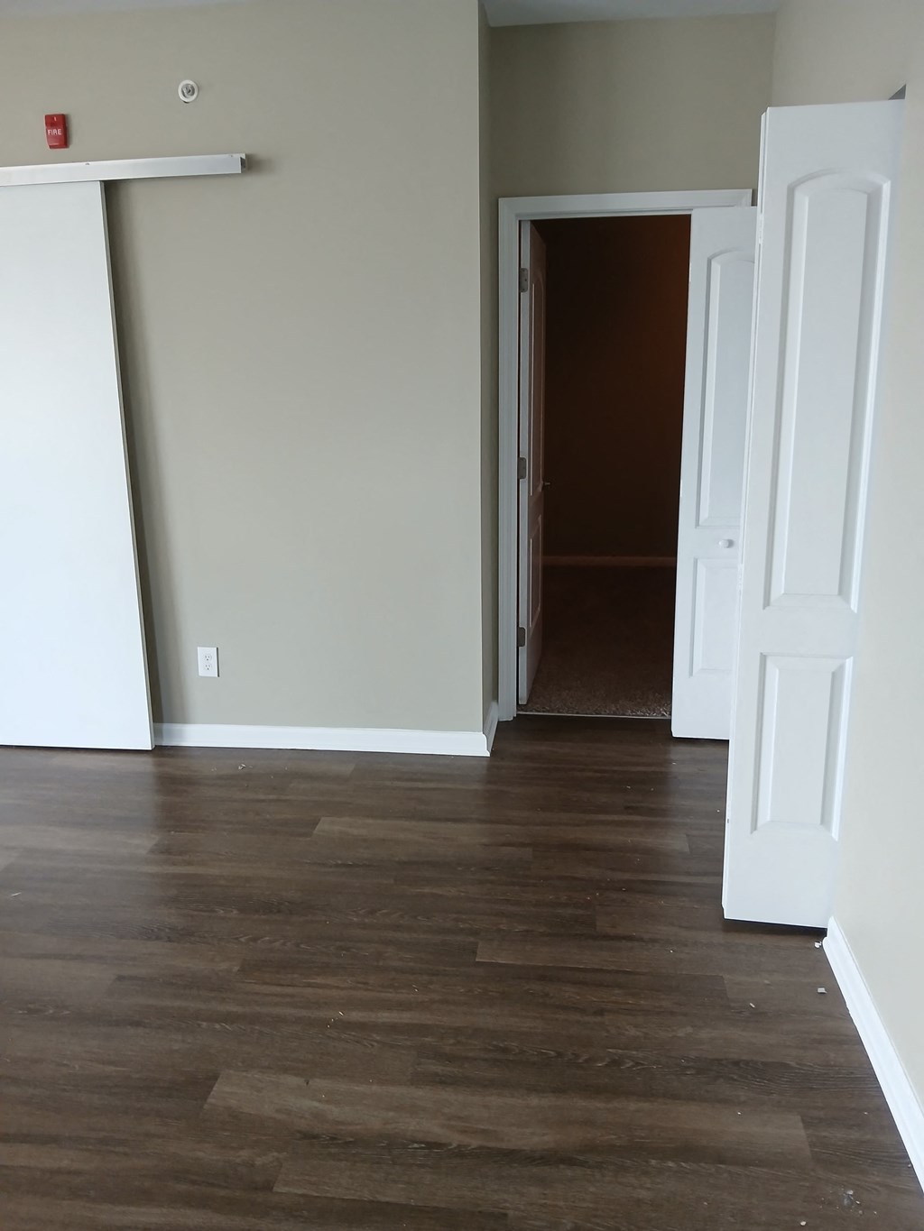 an empty living room with wood floors and white doors