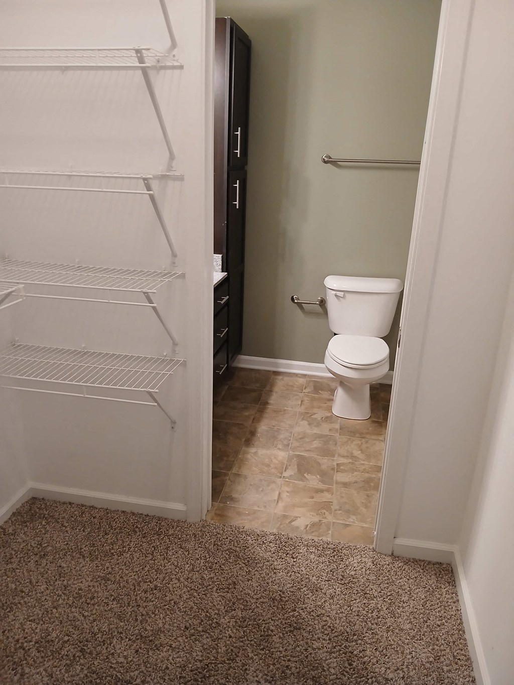 a bathroom with a toilet and an empty closet