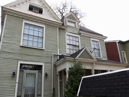 A grey house with a red roof and a white door.