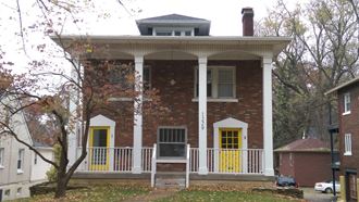 a red brick house with yellow doors and a porch