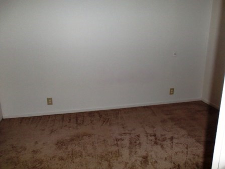 a empty room with a white wall and a brown floor
