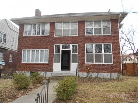 a brick house with a black door and a sidewalk