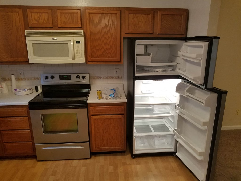 an empty refrigerator in a kitchen with a stove and microwave