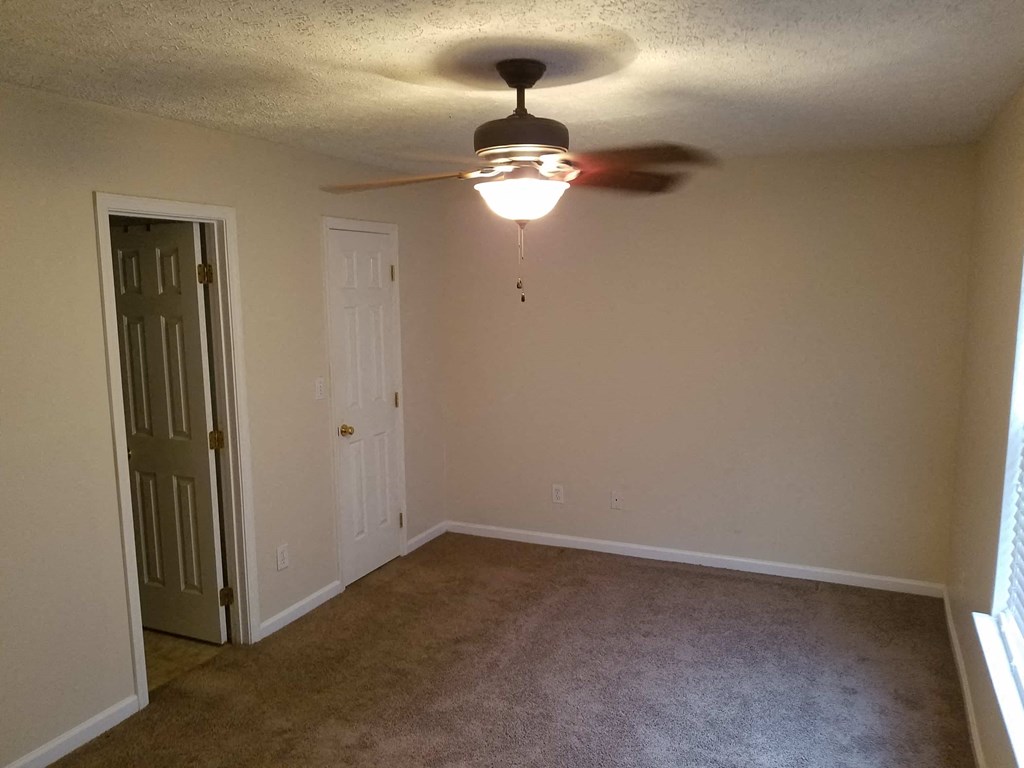 a empty room with a ceiling fan and a door