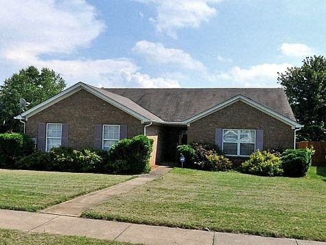 a brick house with a lawn and a sidewalk