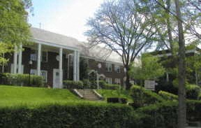 a large house with a lawn and trees in front of it