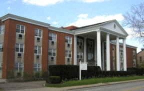 a large brick building with columns and a sign in front