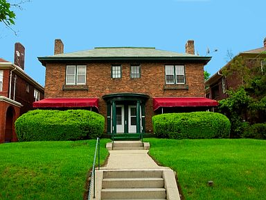 A red brick house with a green door and a red awning.
