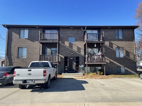 A white pickup truck is parked in front of a brick apartment building.
