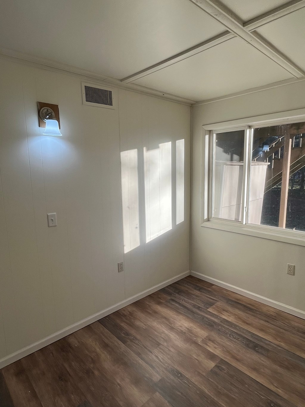 A room with a window and a wood floor.