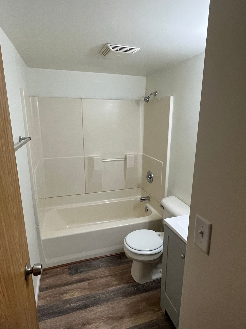 A white toilet sits next to a bathtub in a small bathroom.
