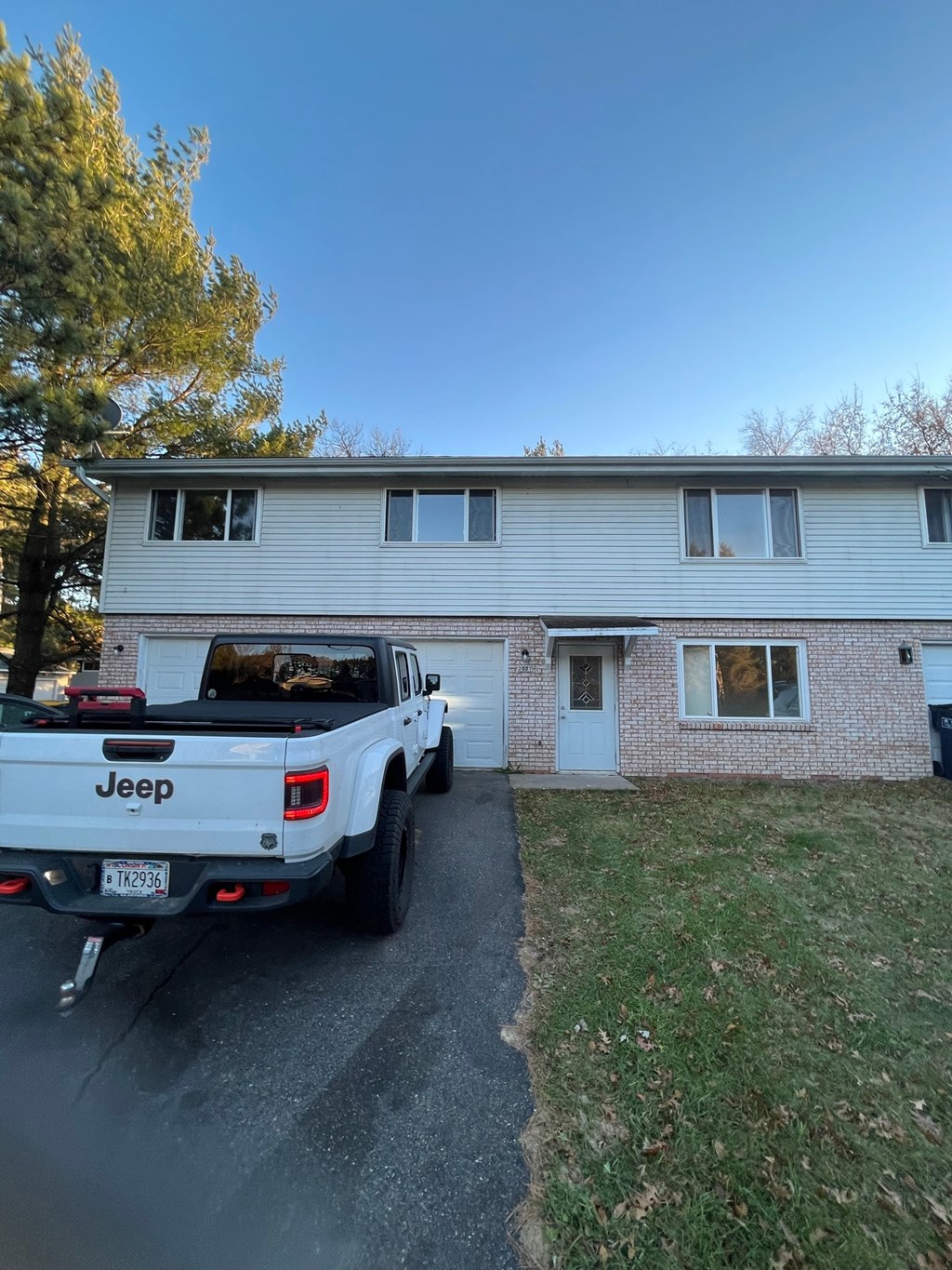 A white Jeep is parked in front of a house.