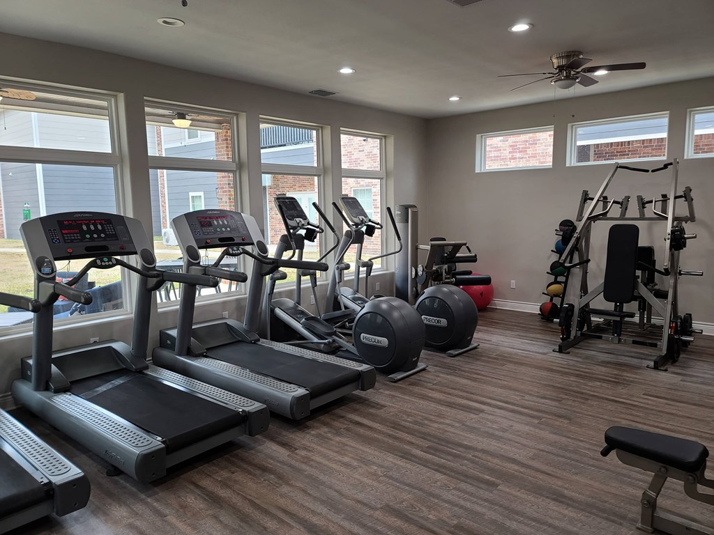 a gym with cardio equipment and windows in a building