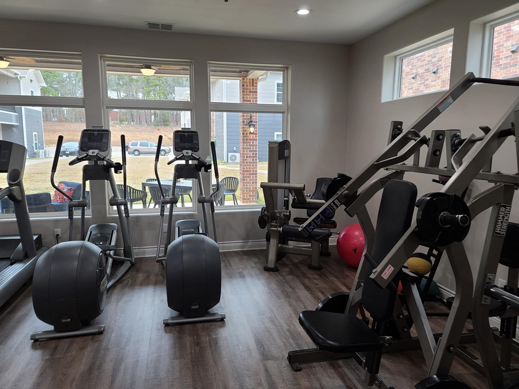 a gym with cardio equipment and windows in a building