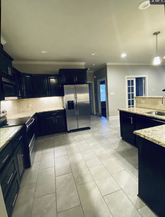 a large kitchen with black cabinets and a stainless steel refrigerator