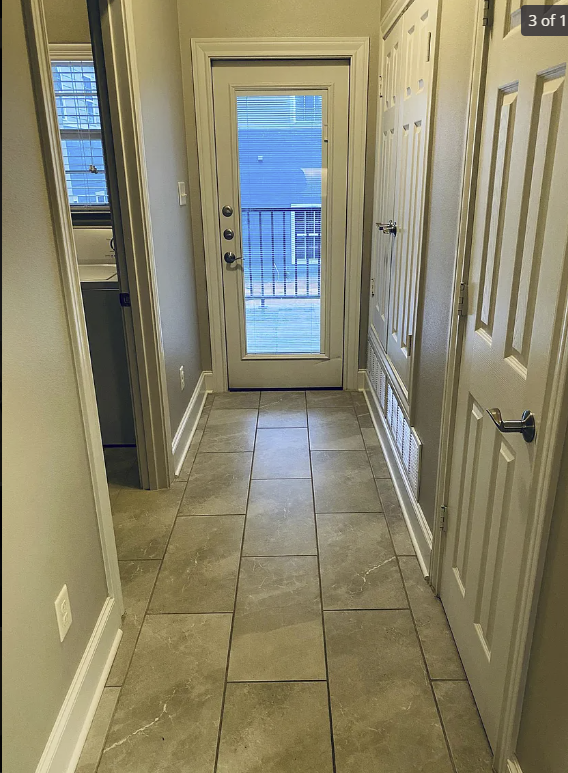 a hallway with tile floors and a door to a balcony