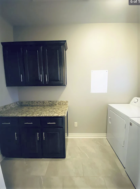A kitchen with black cabinets and a granite countertop.