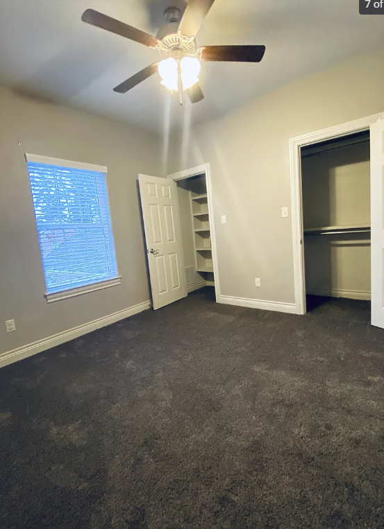 a carpeted room with a ceiling fan and a closet