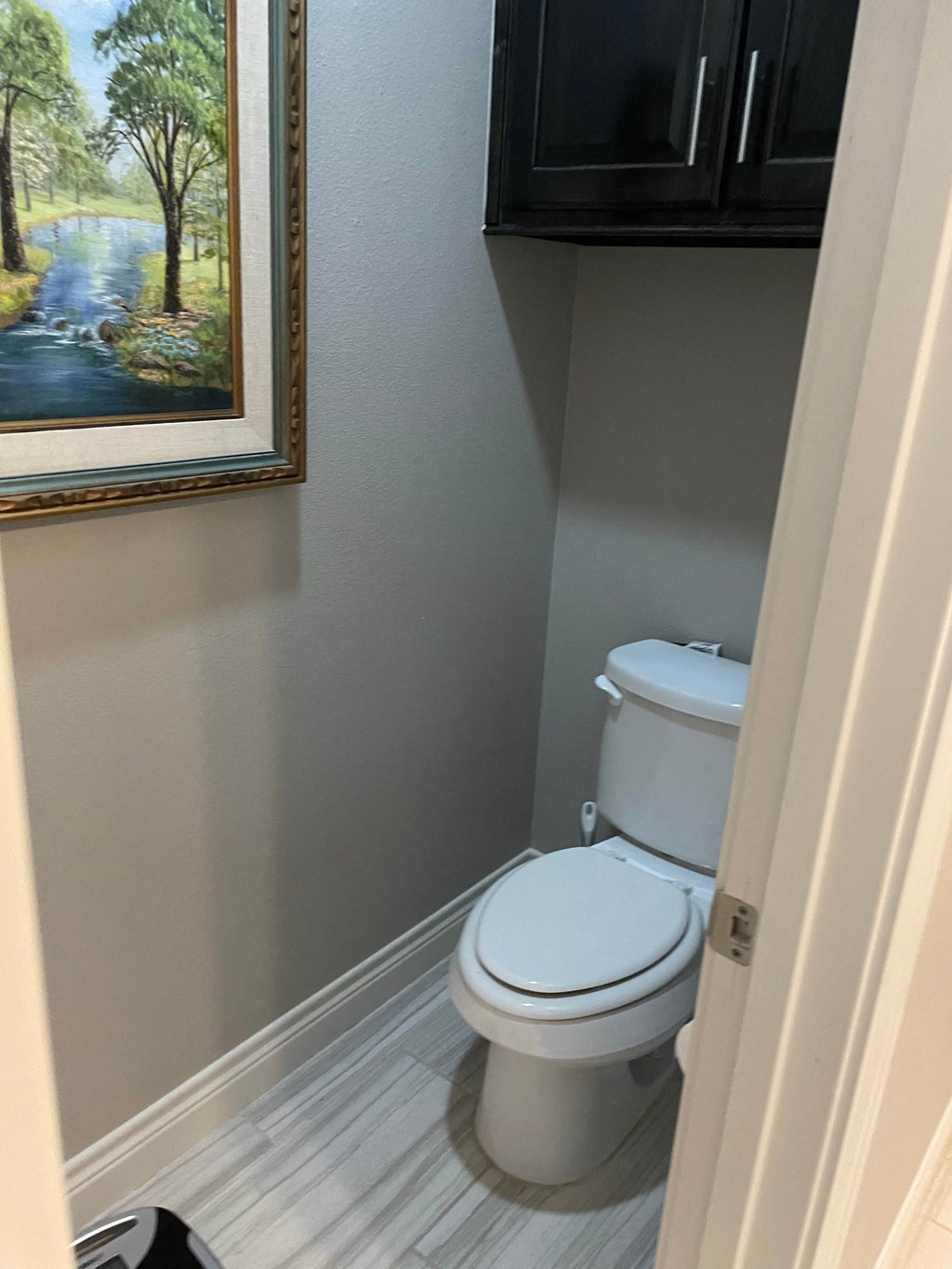 a small bathroom with a toilet and a painting on the wall