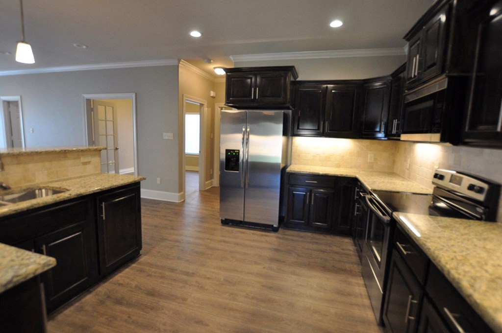 a kitchen with black cabinets and a stainless steel refrigerator