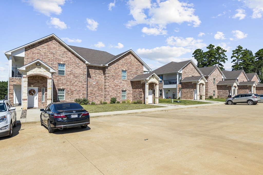 an empty parking lot in front of a brick house