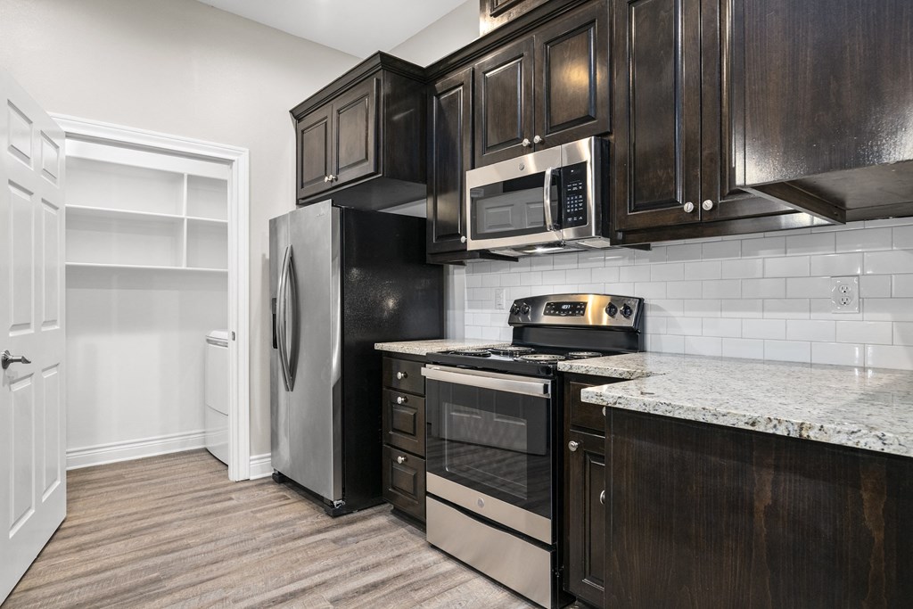 a kitchen with black cabinets and stainless steel appliances