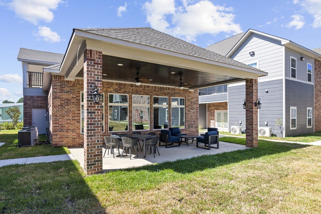 a covered patio with a table and chairs in a backyard