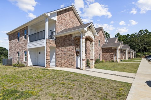 A two-story brick house with a balcony on the upper floor.