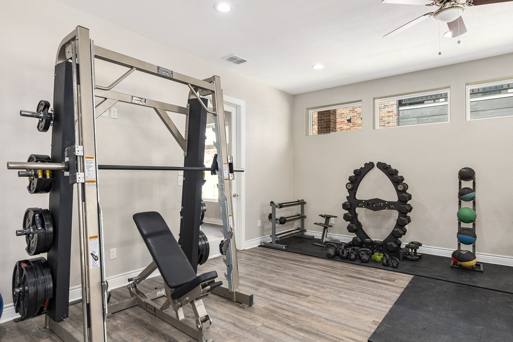a home gym with weights and equipment and a ceiling fan