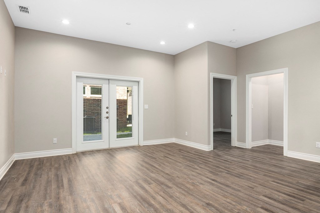 the living room of a new home with doors and a wood floor