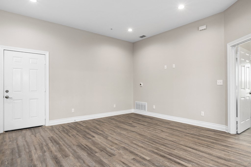 an empty living room with wood flooring and a white door