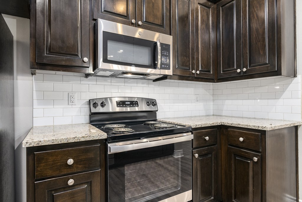 the kitchen of a home with dark wood cabinets and stainless steel appliances