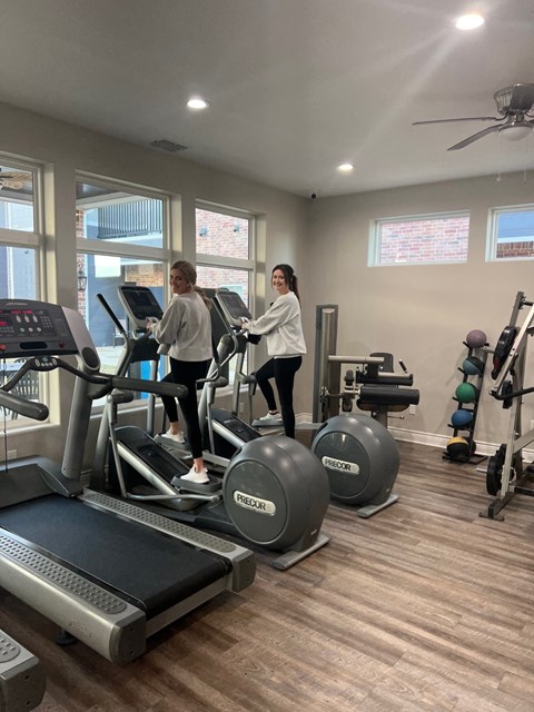 Two people are exercising on treadmills in a gym.