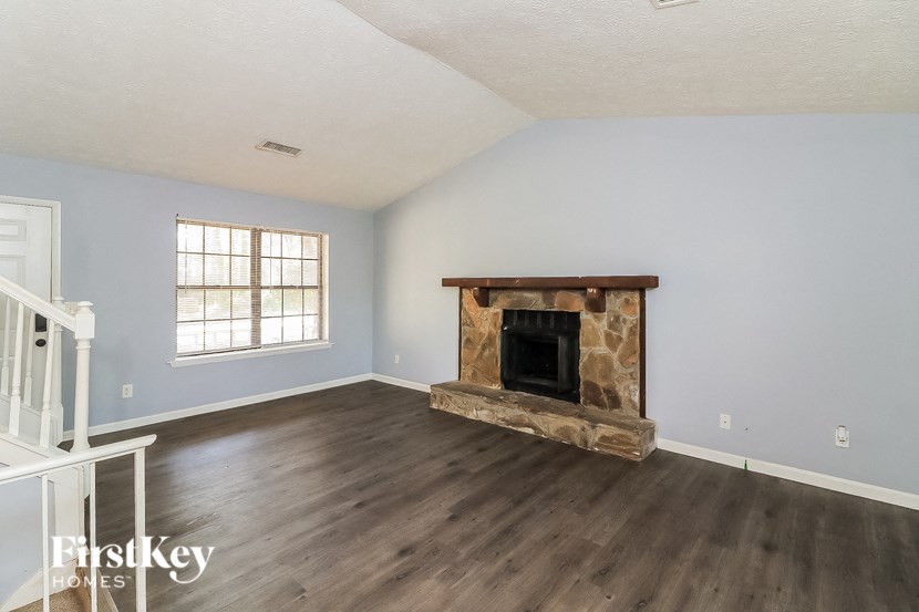 the living room of a home with a fireplace and wooden floors