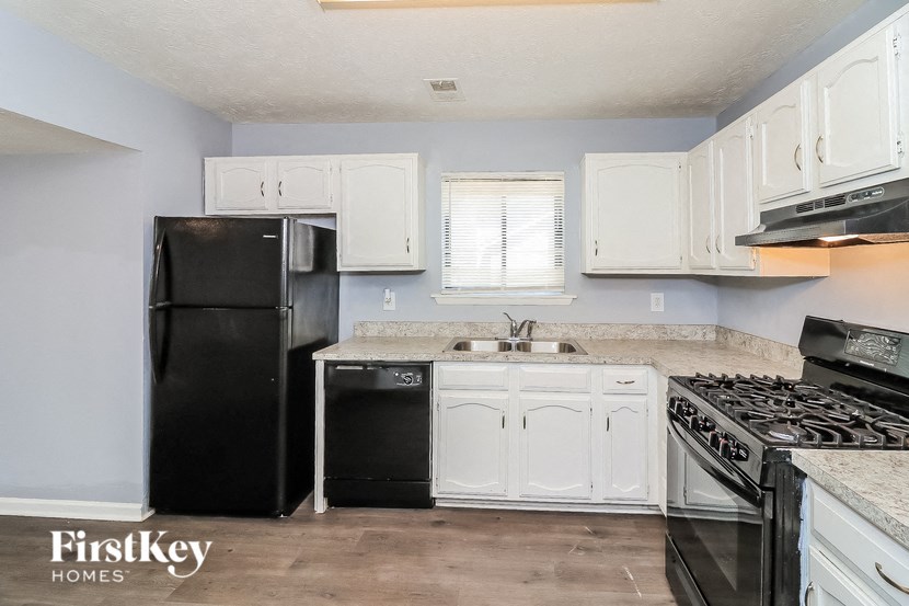 a white kitchen with black appliances and white cabinets