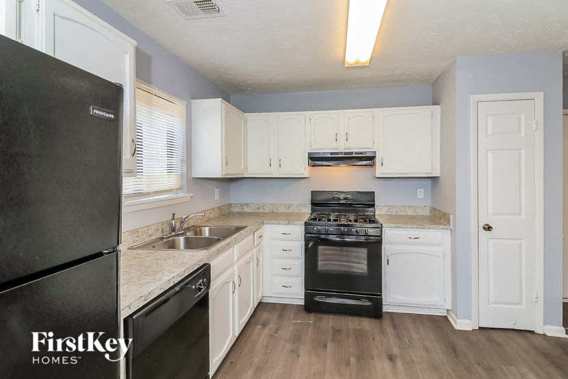 a kitchen with white cabinets and black appliances