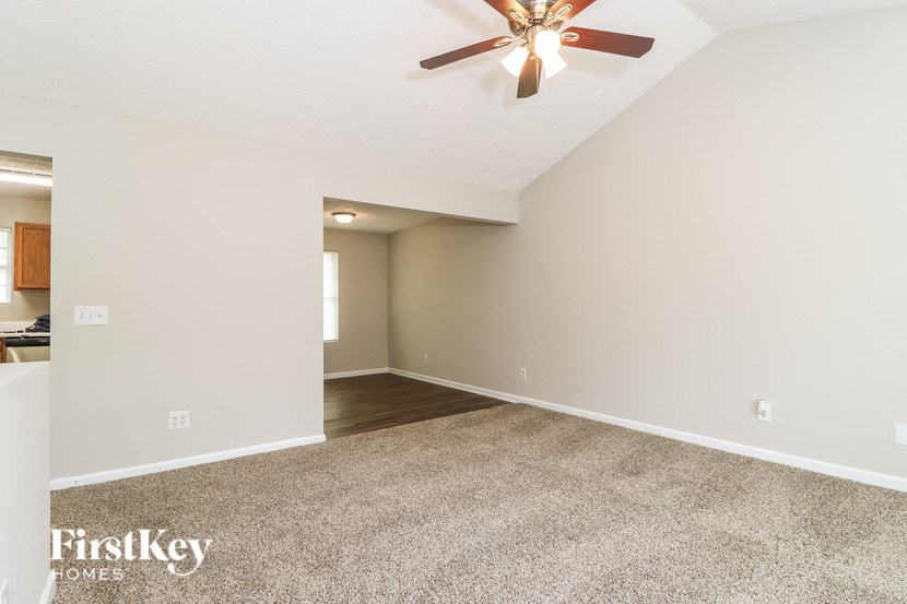 A spacious room with a ceiling fan and carpeted floor.