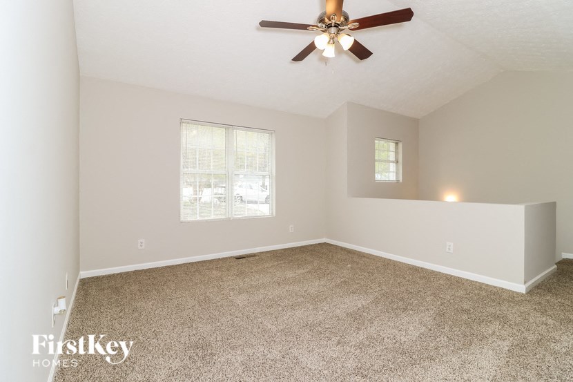 A spacious room with a ceiling fan and carpeted floor.