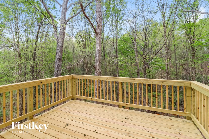 A wooden deck with a railing and trees in the background.