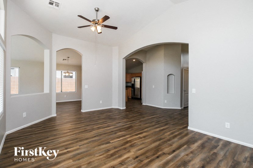 A spacious room with wooden floors and a ceiling fan.