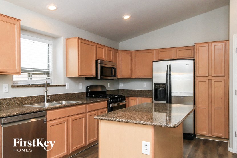 A kitchen with brown cabinets and a granite countertop.