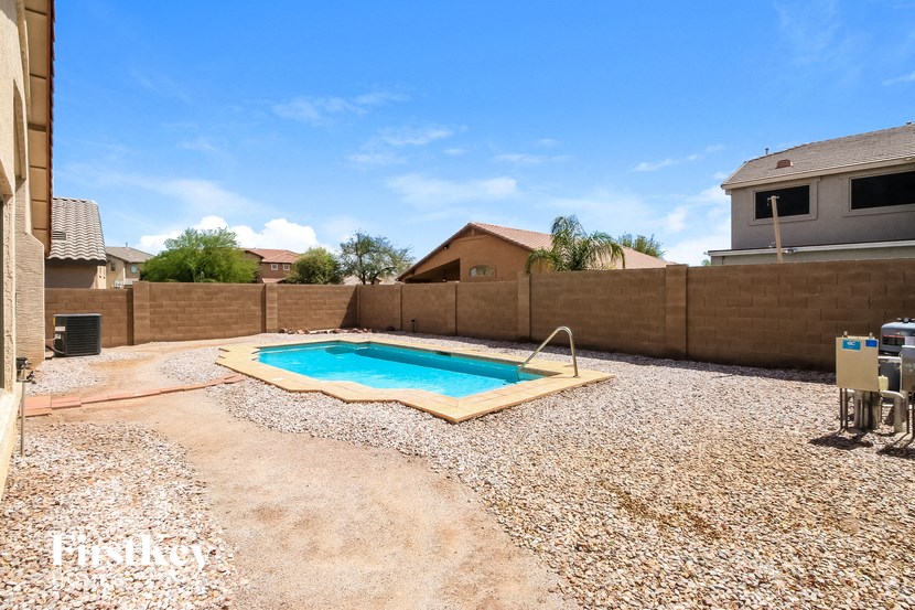 A backyard with a pool and patio furniture.